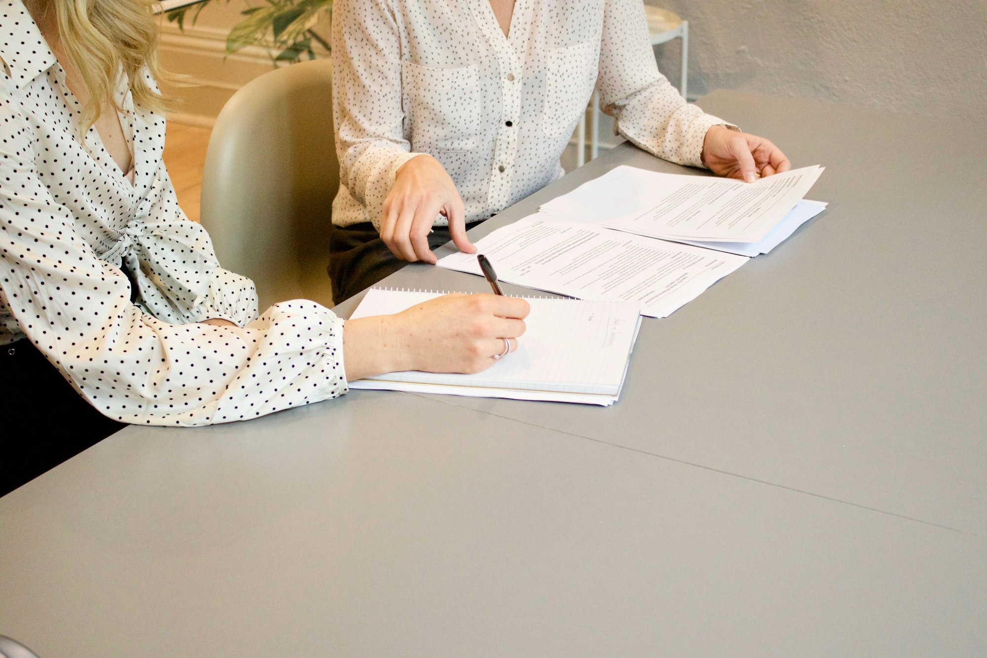 Hand unterschreibt ein Dokument am Besprechungstisch