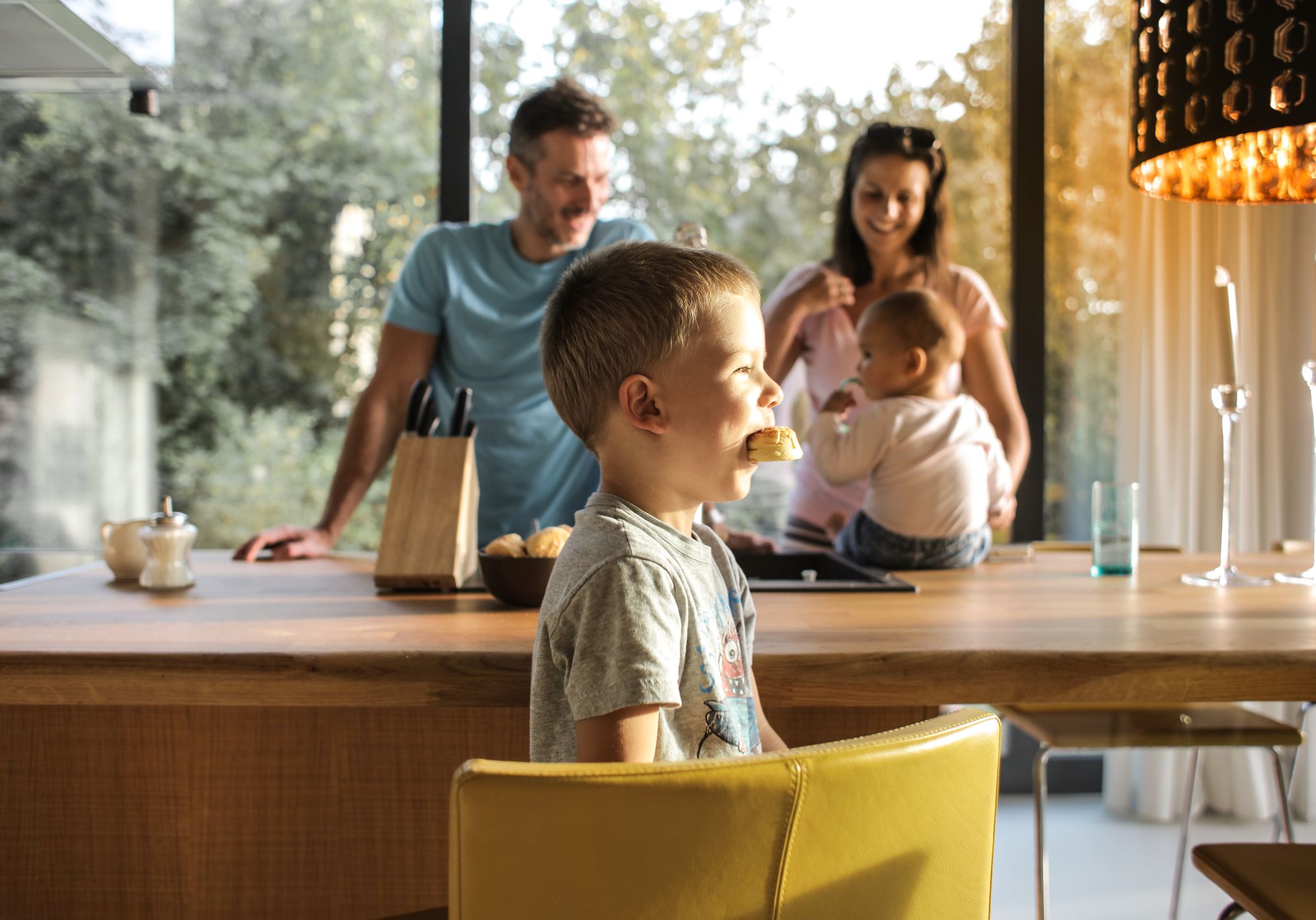Eltern mit zwei kleinen Kindern am Küchentisch zu Hause